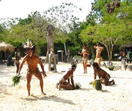 Bailarines con trajes taínos actuando sobre la arena