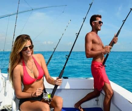 Mujer y hombre con cañas de pesca en la popa de un barco