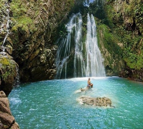 La cascada El Limón cae sobre una poza turquesa con una bañista