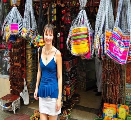 Mujer ante una tienda de bolsos tejidos de colores